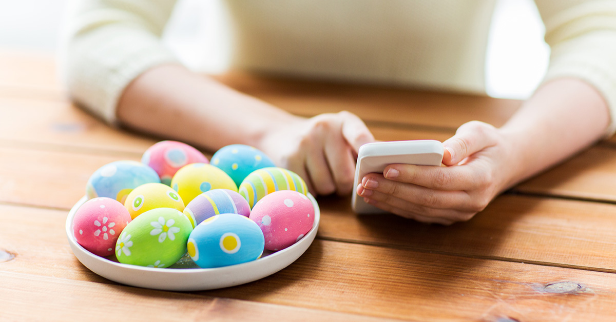 Decorated Easter eggs near a person holding a phone