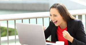 excited woman looking at a laptop