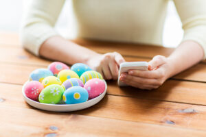 Decorated Easter Egg near a person holding a phone